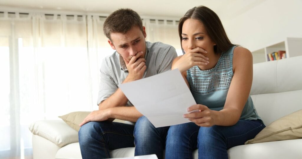 Upset couple on couch looking at paper